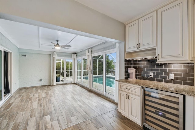 kitchen with light stone counters, visible vents, light wood finished floors, wine cooler, and backsplash