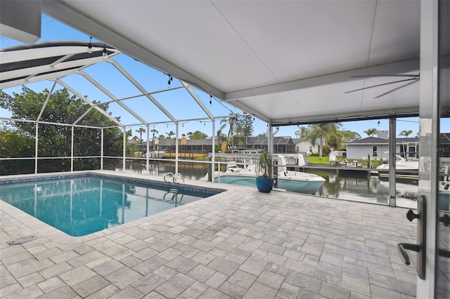 pool featuring glass enclosure, a patio, and a water view