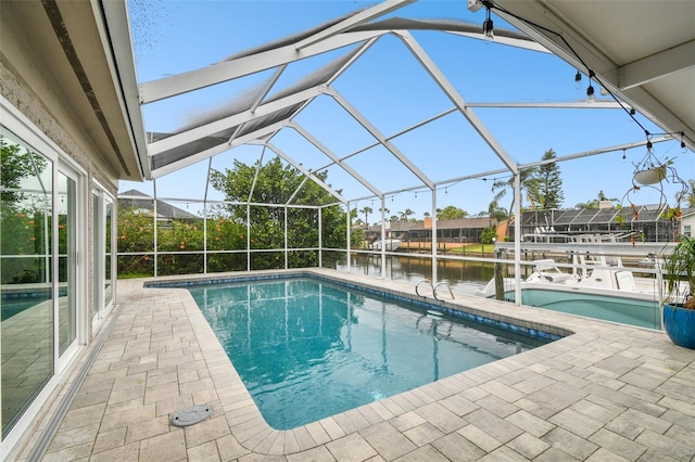 outdoor pool featuring glass enclosure, a patio, and a water view