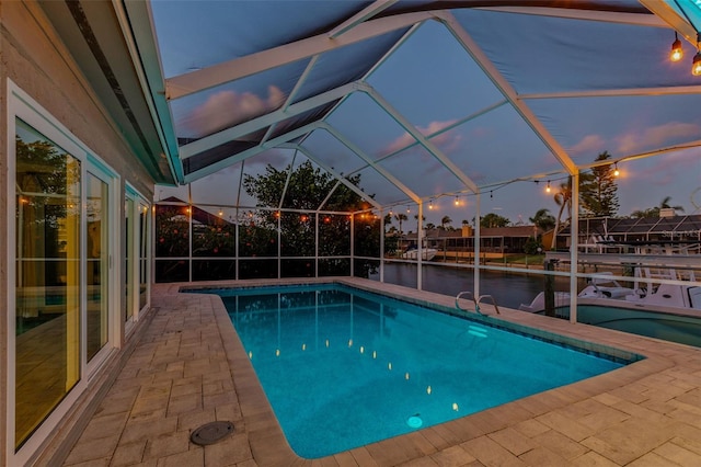 pool featuring a lanai, a patio, and a water view