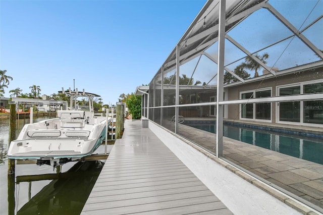 dock area with an outdoor pool, a water view, and a lanai