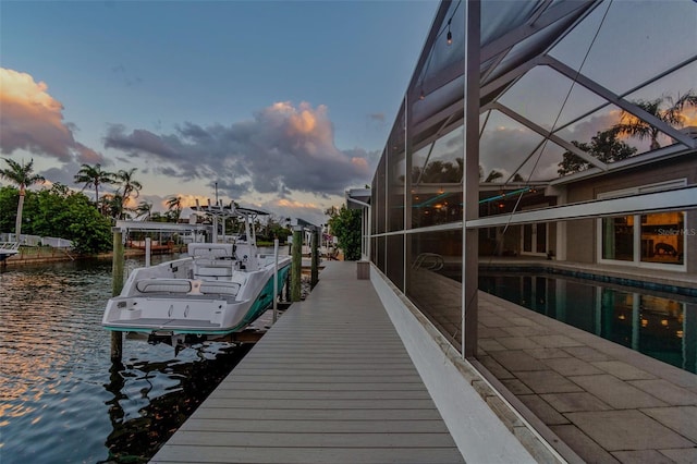 view of dock featuring glass enclosure, a water view, and boat lift