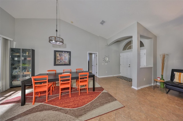 dining area featuring visible vents, baseboards, high vaulted ceiling, arched walkways, and tile patterned floors