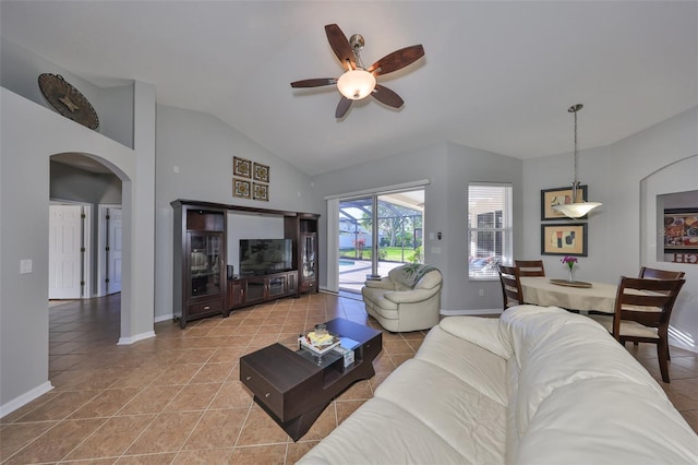 living area featuring arched walkways, baseboards, lofted ceiling, and light tile patterned flooring