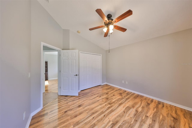 unfurnished bedroom with light wood finished floors, baseboards, vaulted ceiling, a closet, and a ceiling fan