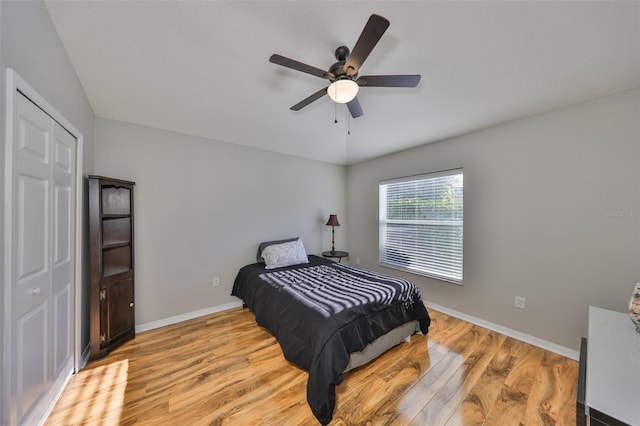 bedroom with a closet, baseboards, light wood-style floors, and a ceiling fan