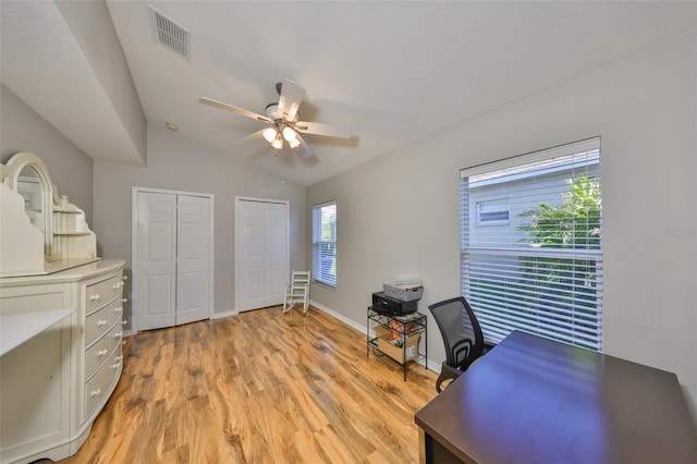 office area featuring visible vents, baseboards, light wood-style floors, lofted ceiling, and ceiling fan