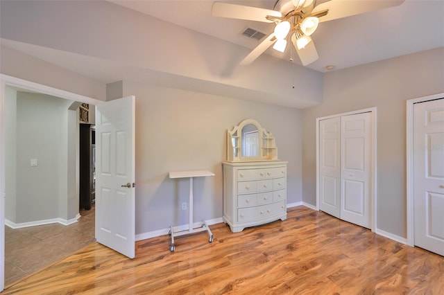 unfurnished bedroom with visible vents, a ceiling fan, baseboards, and wood finished floors