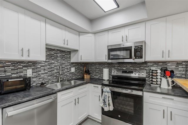 kitchen featuring a sink, decorative backsplash, appliances with stainless steel finishes, and white cabinetry