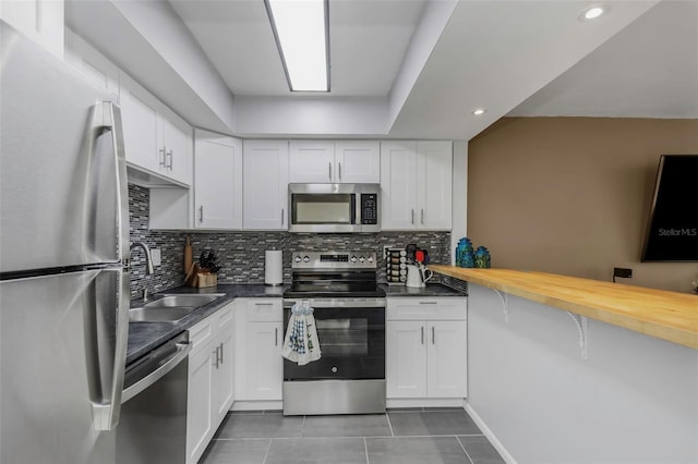 kitchen featuring white cabinets, tasteful backsplash, appliances with stainless steel finishes, and a sink