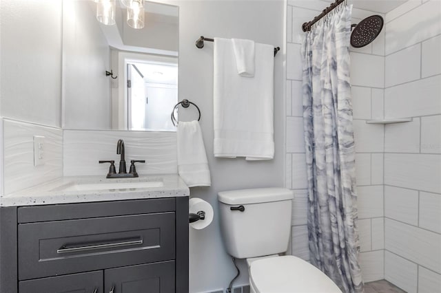 bathroom with toilet, vanity, and a tile shower