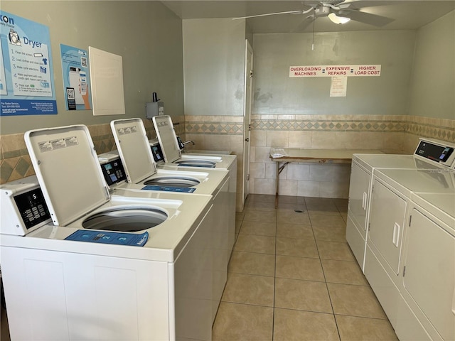 shared laundry area featuring a wainscoted wall, light tile patterned flooring, independent washer and dryer, tile walls, and a ceiling fan