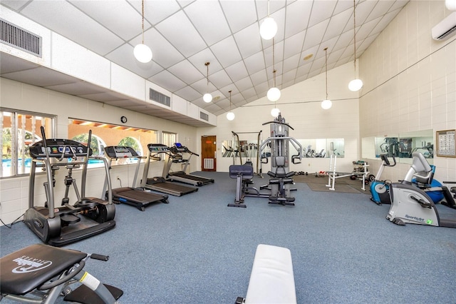 gym featuring high vaulted ceiling, visible vents, and a wall mounted AC