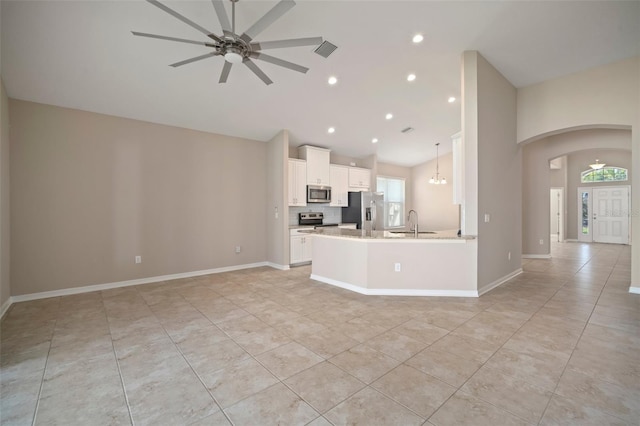 kitchen with visible vents, open floor plan, arched walkways, stainless steel appliances, and a sink