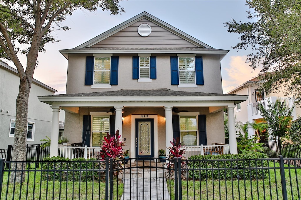 view of front of property with a porch, a ceiling fan, a fenced front yard, and stucco siding