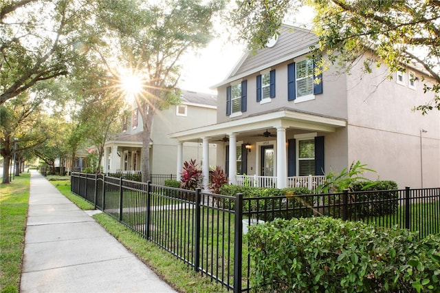 view of front of house featuring stucco siding, a ceiling fan, a fenced front yard, a porch, and a front yard