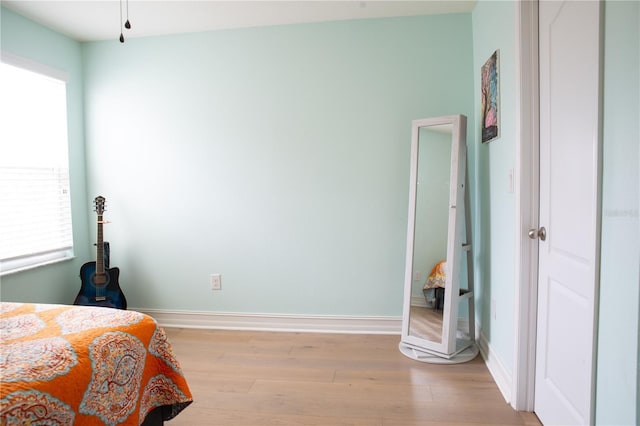 bedroom featuring light wood finished floors and baseboards