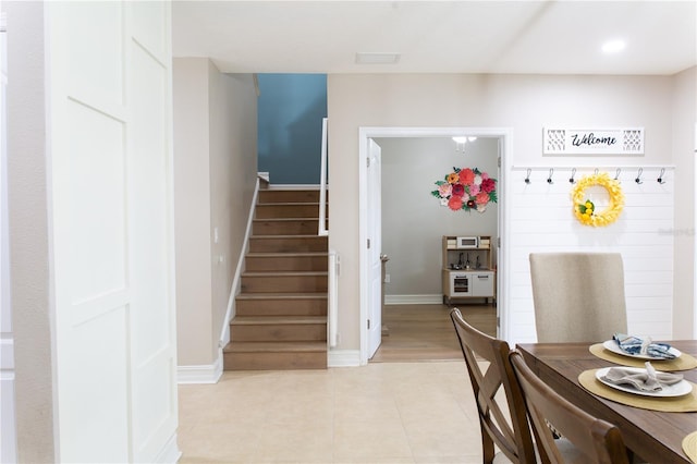 dining room featuring light tile patterned floors, stairs, and baseboards