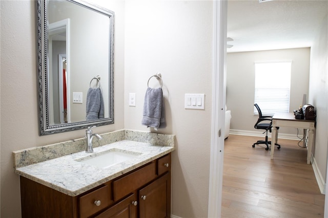 bathroom with baseboards, wood finished floors, and vanity