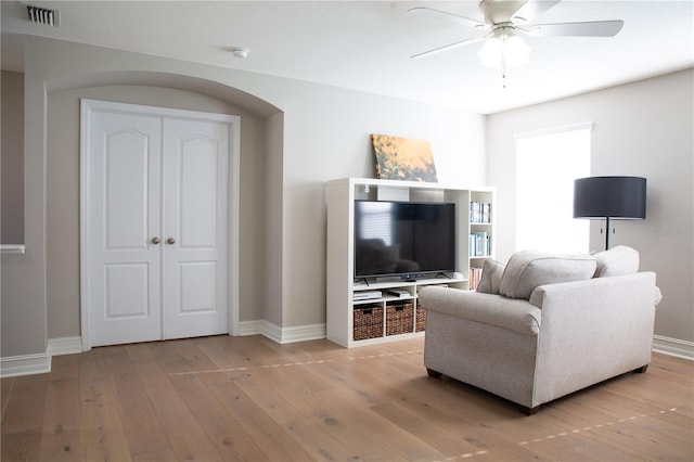 living room with baseboards, a ceiling fan, visible vents, and light wood-type flooring