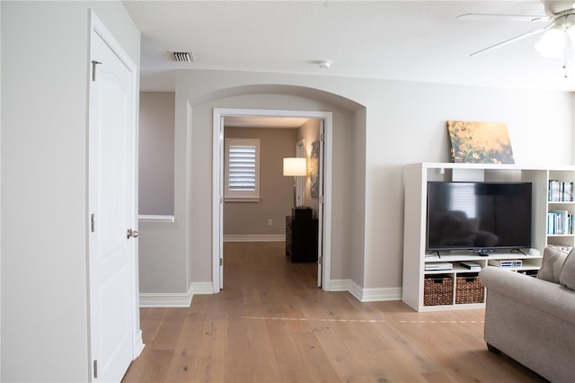 corridor with light wood-style flooring, visible vents, arched walkways, and baseboards