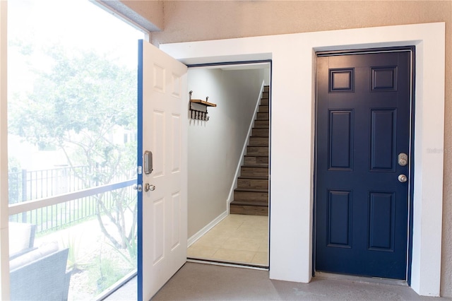 entryway featuring light tile patterned floors, stairway, plenty of natural light, and baseboards