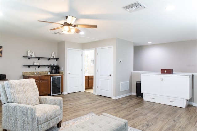 sitting room featuring light wood-style floors, bar, beverage cooler, and visible vents