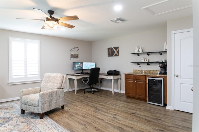 office space with wood finished floors, visible vents, baseboards, indoor wet bar, and wine cooler