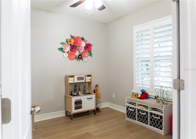 game room with baseboards, light wood-style floors, and ceiling fan