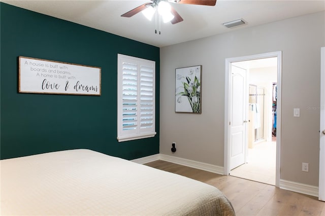 bedroom with ceiling fan, visible vents, baseboards, and wood finished floors