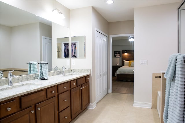 ensuite bathroom featuring a sink, a tub, double vanity, and tile patterned flooring