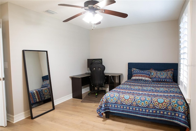 bedroom featuring visible vents, baseboards, multiple windows, and wood finished floors