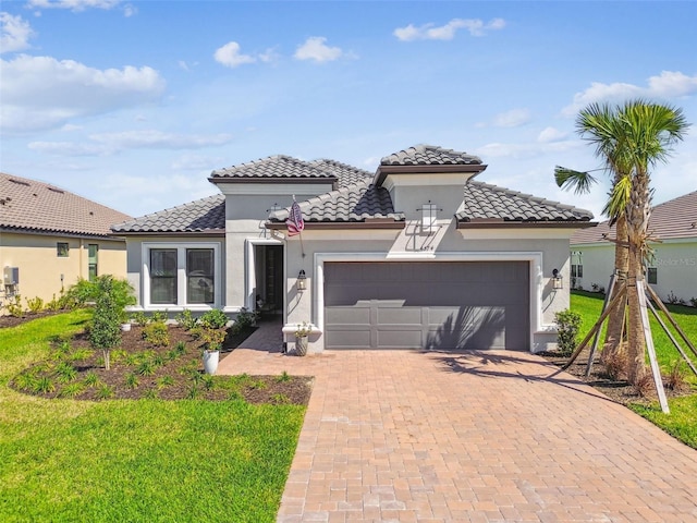 mediterranean / spanish-style house featuring a tiled roof, decorative driveway, a garage, and stucco siding