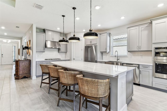 kitchen with under cabinet range hood, stainless steel appliances, and gray cabinetry