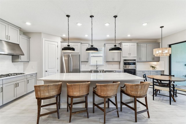 kitchen featuring under cabinet range hood, gray cabinets, and appliances with stainless steel finishes