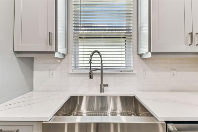 room details with light stone counters, backsplash, and a sink