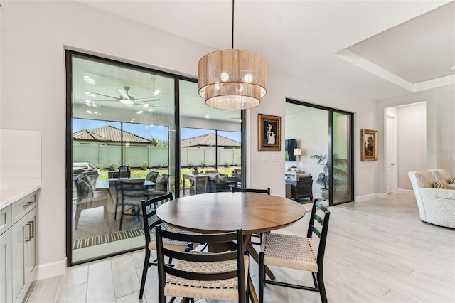 dining space featuring light wood finished floors, baseboards, a sunroom, and ceiling fan