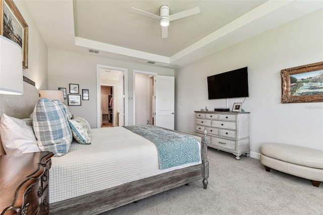 bedroom with a tray ceiling, light carpet, baseboards, and ceiling fan