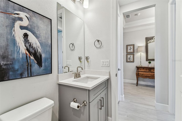 bathroom with vanity, wood finished floors, visible vents, crown molding, and toilet