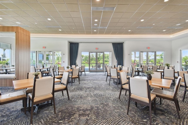 dining space with a healthy amount of sunlight, french doors, carpet, and a towering ceiling