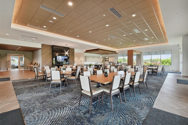 dining space featuring visible vents, a raised ceiling, and wood finished floors