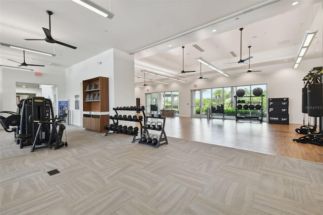 exercise room with a high ceiling, light colored carpet, and visible vents