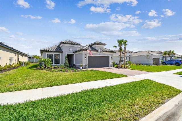 mediterranean / spanish-style house with an attached garage, a tile roof, decorative driveway, and a front yard