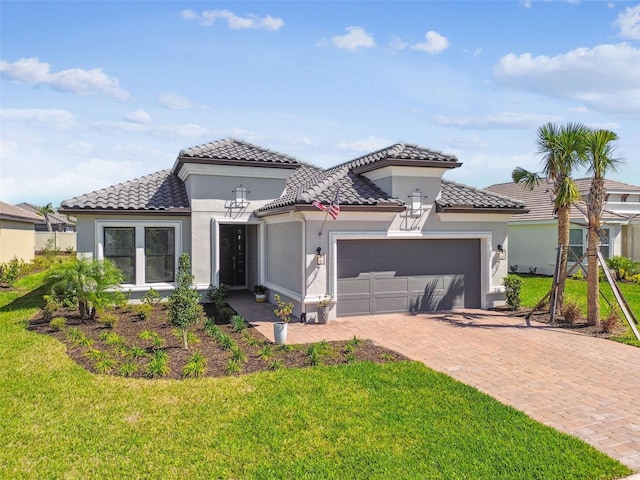 mediterranean / spanish-style house featuring stucco siding, a front lawn, a tile roof, decorative driveway, and an attached garage