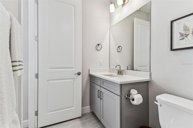 bathroom with toilet, vanity, and wood finished floors