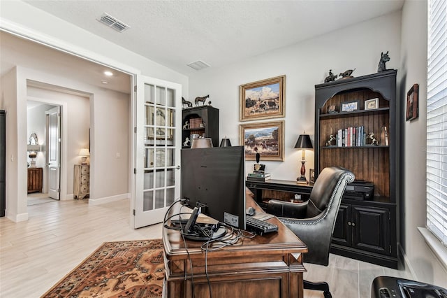 office space featuring visible vents, baseboards, light wood-type flooring, french doors, and a textured ceiling