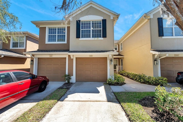 multi unit property featuring concrete driveway, an attached garage, and stucco siding