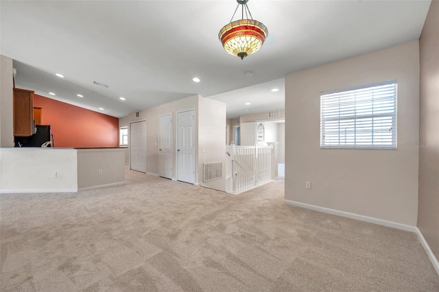 unfurnished living room with light carpet, visible vents, recessed lighting, and lofted ceiling