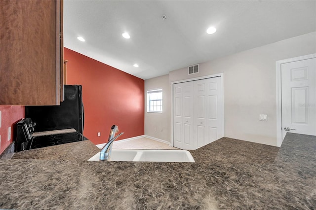 kitchen featuring dark countertops, visible vents, vaulted ceiling, black appliances, and a sink