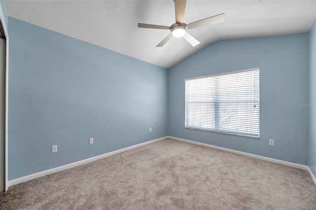 carpeted spare room with baseboards, lofted ceiling, and a ceiling fan